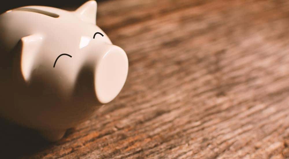 Pink piggybank with a happy expression sitting on a dark brown wooden table