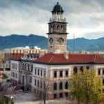Old Colorado Springs building surrounded by trees and other buildings in front of mountains