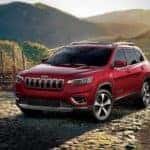 A red 2019 Jeep Cherokee Limited parked in front of rolling vineyards and mountains
