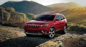 A red 2019 Jeep Cherokee Limited parked in front of rolling vineyards and mountains