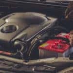 Close up of a technician's hands working under the hood of a vehicle.