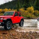 A red Jeep Wrangler leads the way in crossing a Colorado Springs river