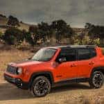 A bight orange certified pre-owned Jeep Renegade a dusty and brown mountain landscape