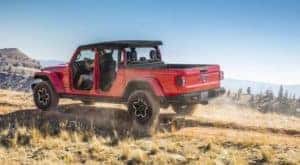A red 2020 Jeep Gladiator with the doors removed driving up a mountain
