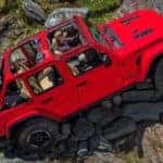 A red 2018 Jeep Wrangler is rock crawling after leaving the dealership where you can find similar used cars in Colorado Springs, CO.