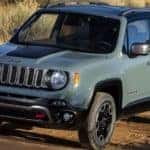 A blue 2016 Jeep Renegade is driving on a dirt road.