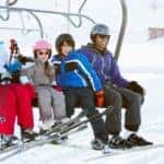 A happy smiling family are on a ski lift.