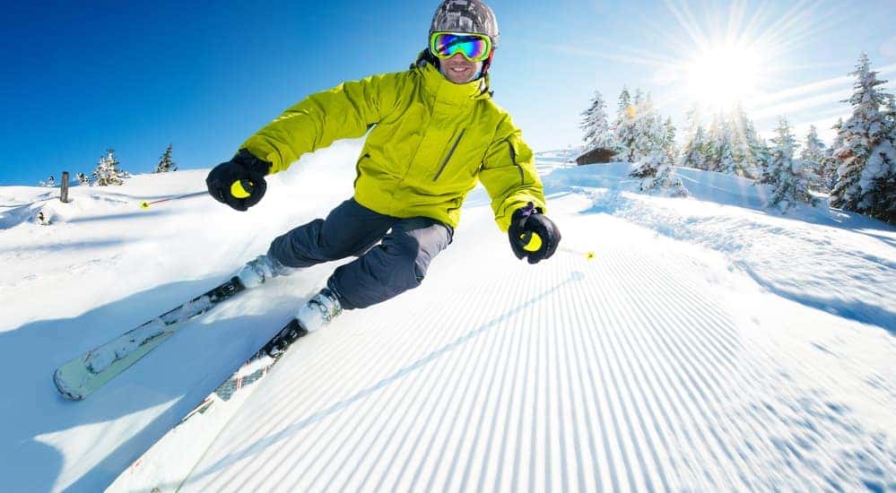 A man is smiling while skiing down a snowy trail.