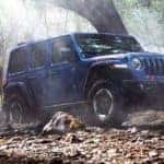 A blue 2020 Jeep Wrangler equipped with some of the best Jeep accessories for 2020 models is off-roading near Colorado Springs, CO.