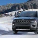 A grey 2020 Jeep Compass, which is a popular option among the Jeep models, is driving on a snowy road in Colorado Springs, CO.