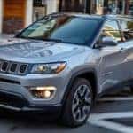 A grey 2020 Jeep Compass is driving past blurred buildings near Colorado Springs, CO.