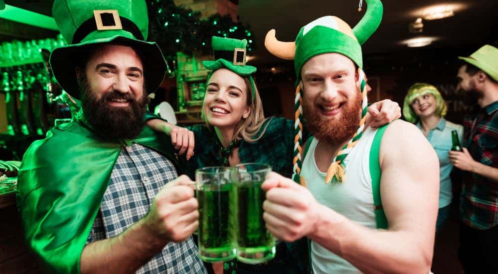 Three friends in St. Patrick's Day outfits share green beers at a bar in Colorado Springs