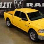 A yellow 2016 Ram 1500 parked in a showroom for used cars in Colorado Springs.