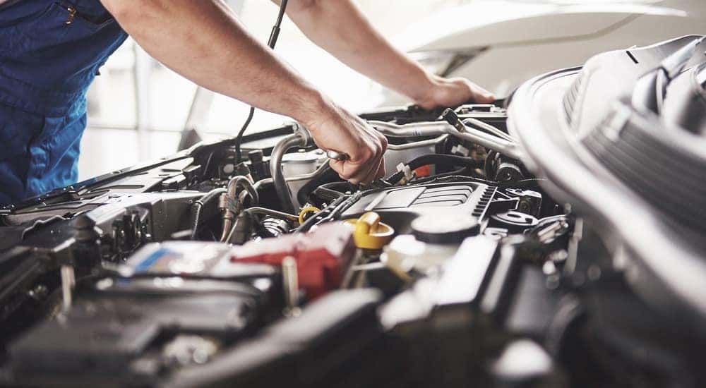 A mechanic is working under the hood of a car.