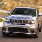 A silver Certified Pre-Owned 2020 Jeep Grand Cherokee is driving around a track.