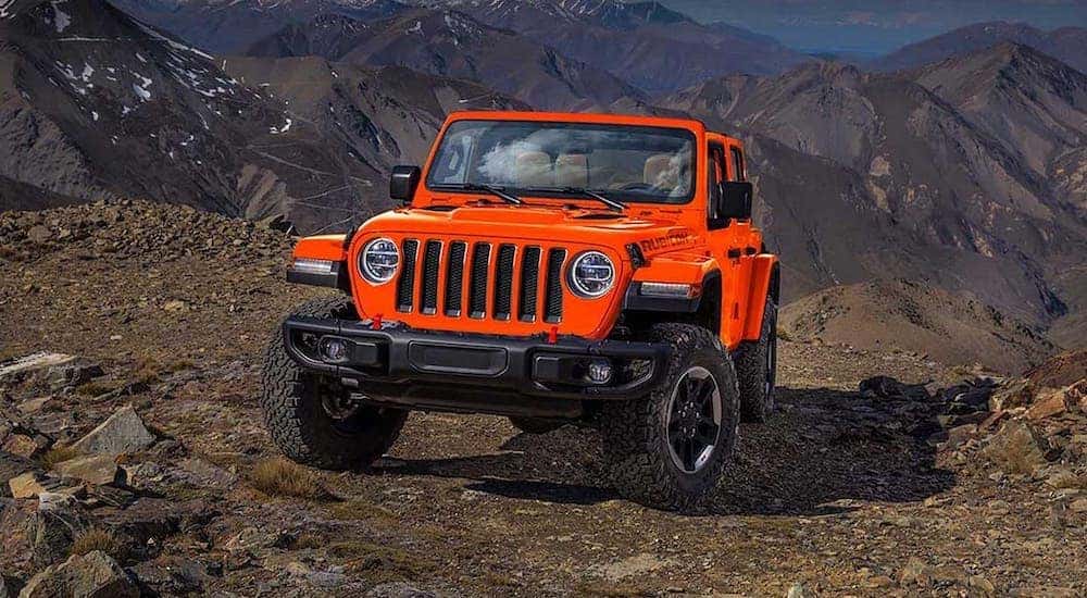 An orange Certified Pre-Owned 2019 Jeep Wrangler Unlimited is shown parked in front of mountains.