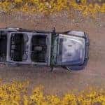 A silver Certified Pre-Owned 2019 Jeep Wrangler Unlimited with no roof is shown from above driving on a dirt road near Colorado Springs.