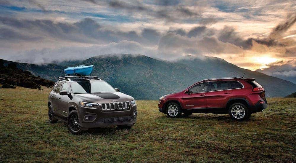 A gray and a red 2020 Jeep Cherokee Trailhawks are parked atop a mountain.