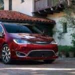 A red 2018 Chrysler Pacifica is parked in front of a villa.