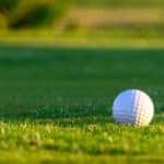 A closeup shows a golf ball on a Denver golf course.
