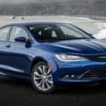 A popular used car for sale near you, a blue 2017 Chrysler 200, is shown parked in front of a beach.