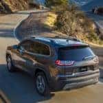 A gray 2019 Jeep Cherokee is driving around a winding road in Colorado Springs.