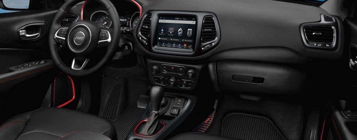 The black interior dashboard with red accents is shown in a 2019 used Jeep Compass.