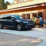 A family is at a market next to a black 2021 Chrysler Pacifica Hybrid after leaving a Colorado Springs Chrysler dealership.