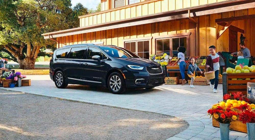 A family is at a market next to a black 2021 Chrysler Pacifica Hybrid after leaving a Colorado Springs Chrysler dealership.