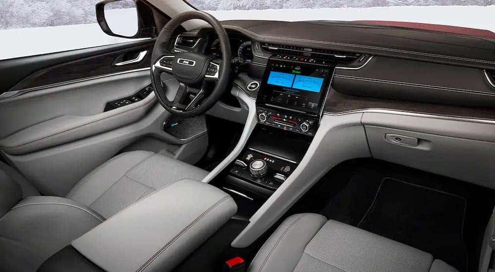 The gray and black front seats and dashboard of a 2021 Jeep Grand Cherokee L are shown.