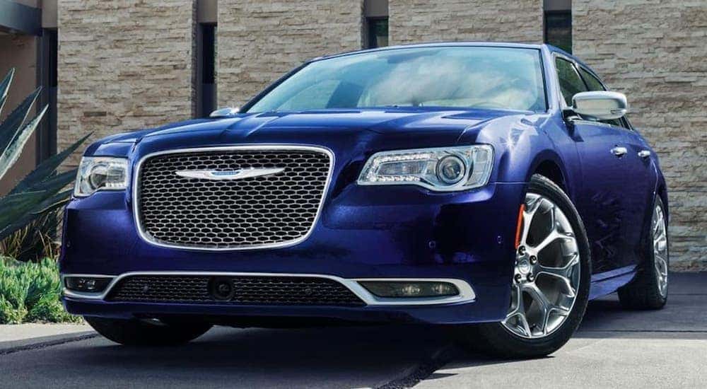 A blue 2018 Chrysler 300 is parked in front of a stone building.