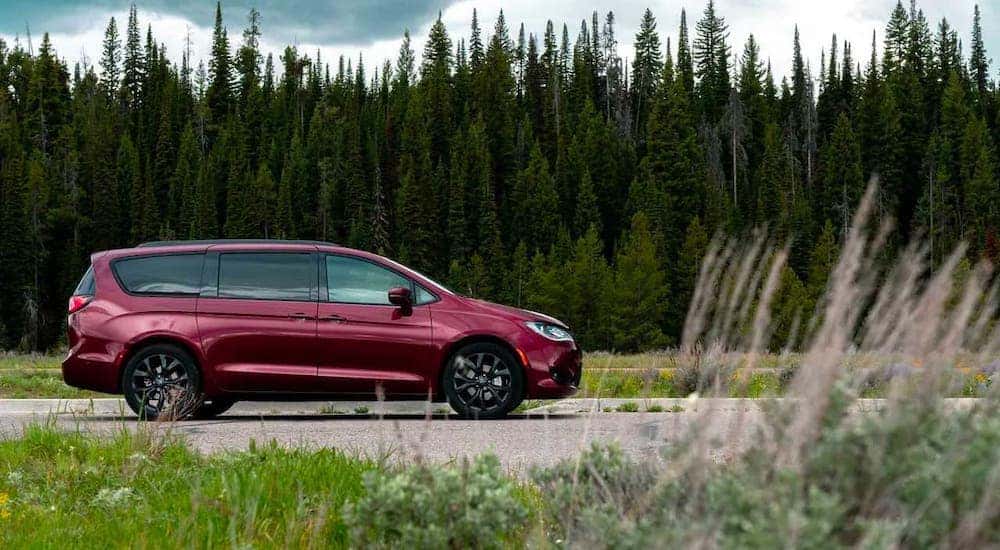 A red 2019 Chevy Pacifica is shown from the side while driving in front of trees.