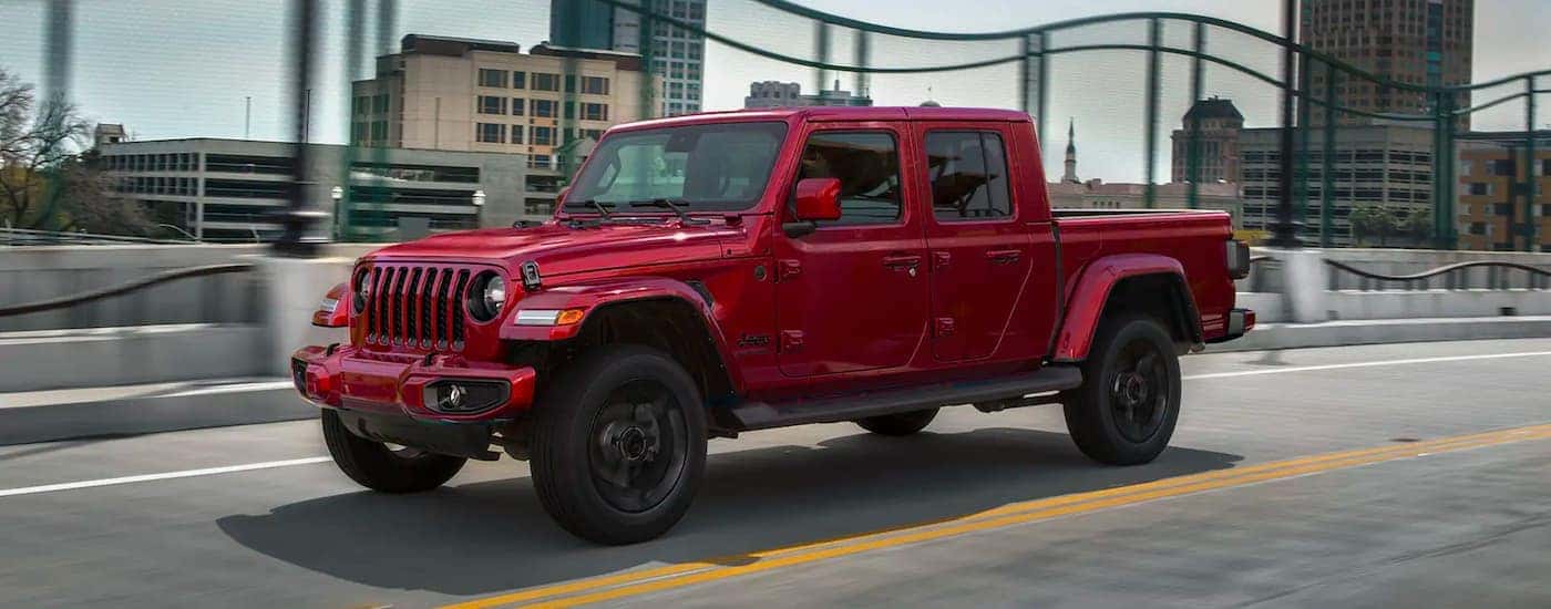 A red 2021 Jeep Gladiator is shown from the side driving in a city.