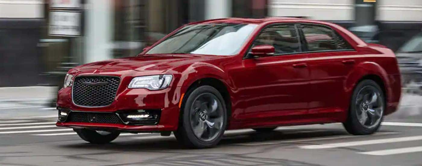 A red 2021 Chrysler 300 is driving on a city street.