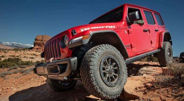 A red 2023 Jeep Wrangler Rubicon 392 is shown off-roading on a dusty desert trail.