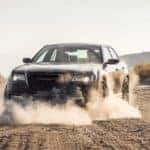 A black 2021 Chrysler 300 is driving on a dirt road.