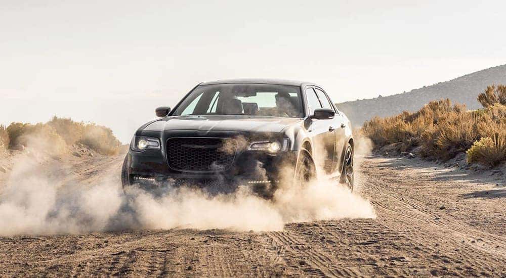 A black 2021 Chrysler 300 is driving on a dirt road after leaving a Chrysler dealer near Black Forest.