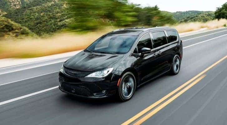 A black 2020 used Chrysler Pacifica is driving past dry grass and trees.