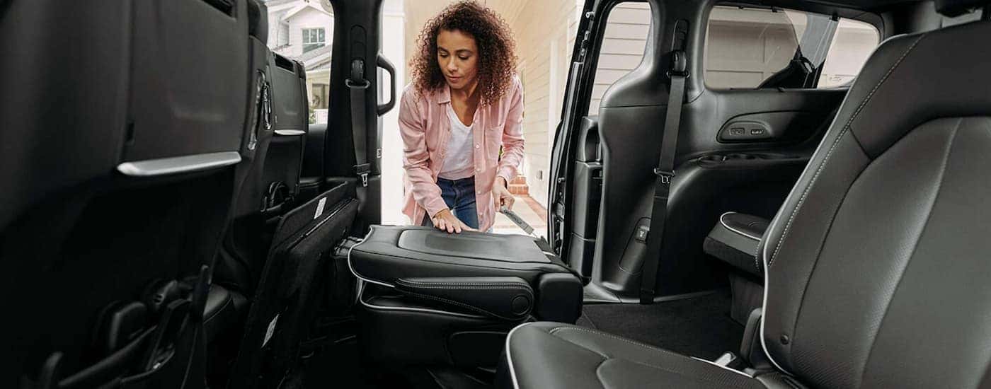 A woman is folding the rear seat down in a 2021 Chrysler Pacifica.