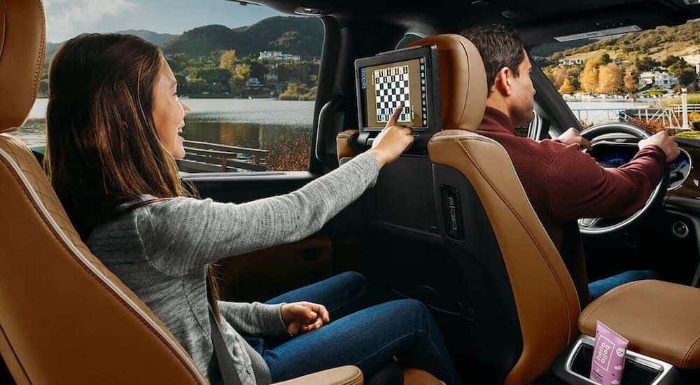 A girl is using the touchscreen in the back seat of a 2021 Chrysler Pacifica.