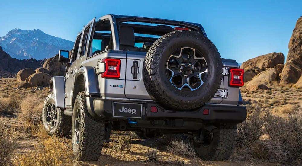 A silver 2021 Jeep Wrangler 4xe is shown from the rear off-roading in the desert.