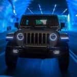 A silver 2021 Jeep Wrangler 4xe is shown from the front driving through a tunnel.