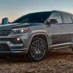 A grey 2022 Jeep Compass is shown by a lake overlooking a city after leaving a Jeep dealership.