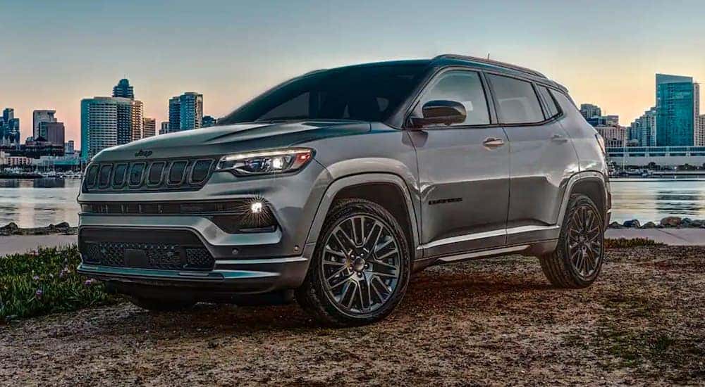 A grey 2022 Jeep Compass is shown by a lake overlooking a city after leaving a Jeep dealership.