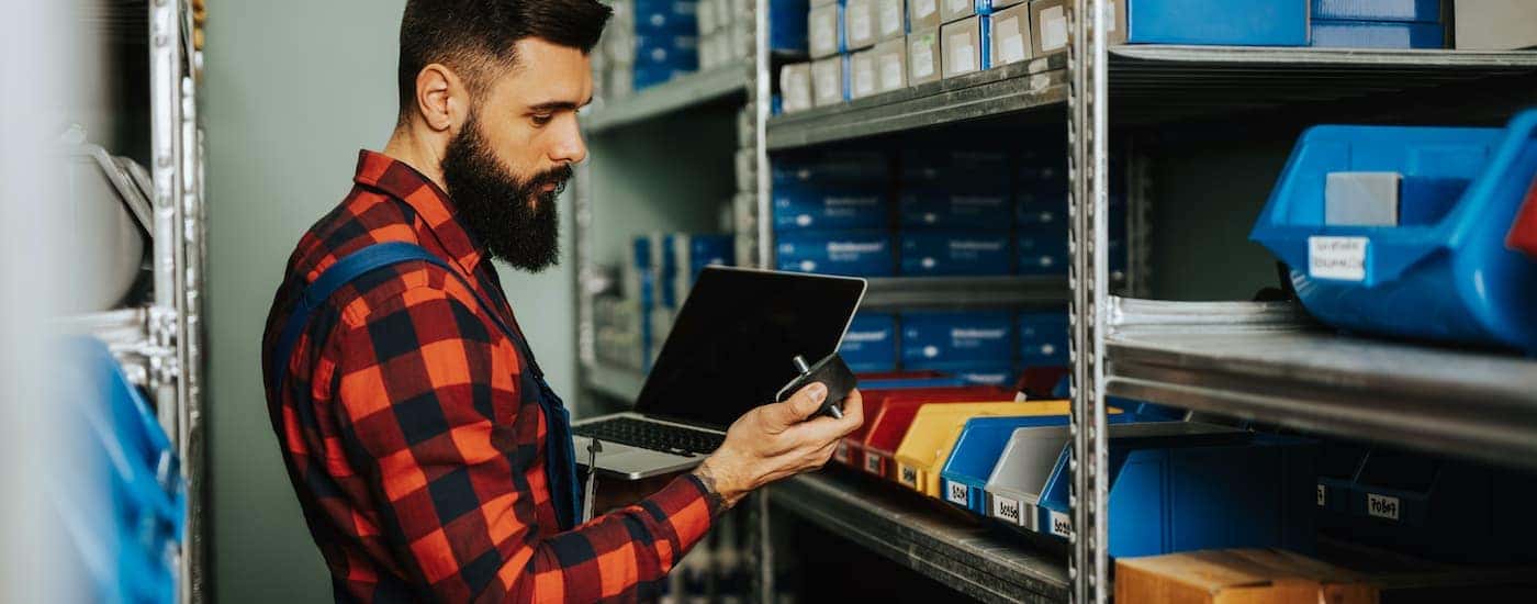 A close up shows a man in a flannel shirt picking replacement parts.