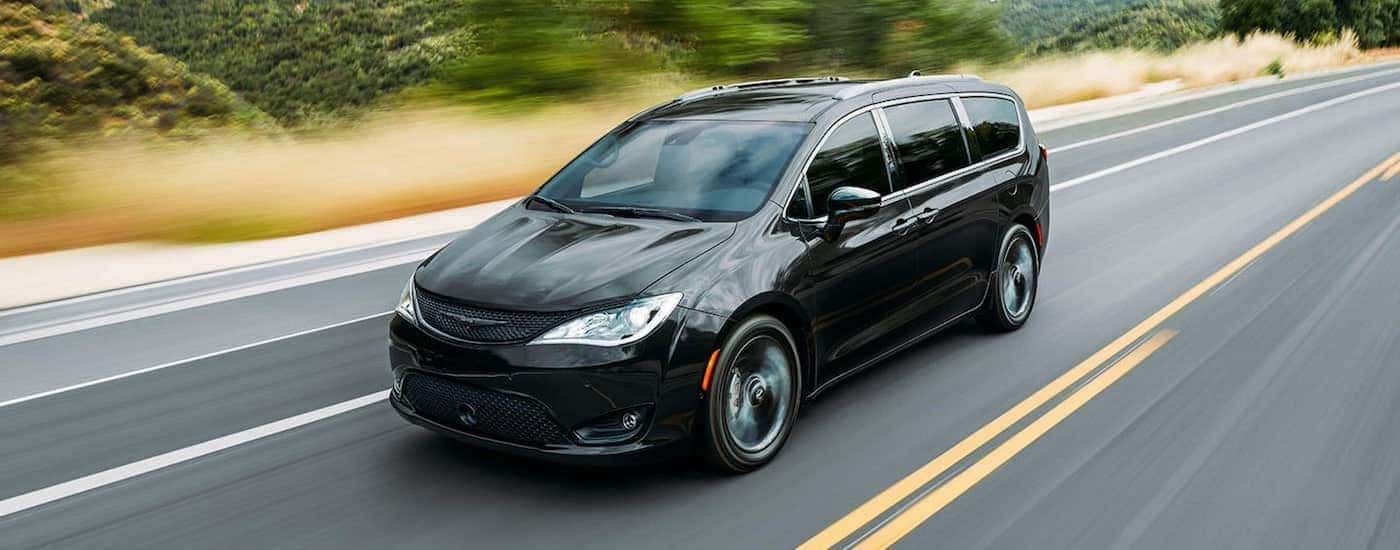A black 2021 Chrysler Pacifica is shown driving down a blurred road.