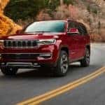 A red 2022 Wagoneer is shown rounding a corner after leaving a Colorado Jeep dealership.