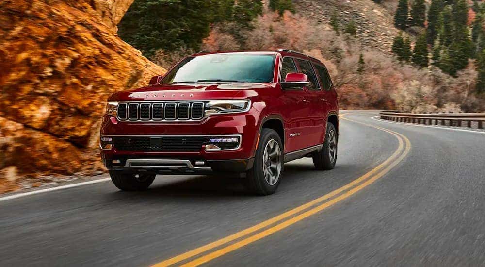 A red 2022 Wagoneer is shown rounding a corner after leaving a Colorado Jeep dealership.
