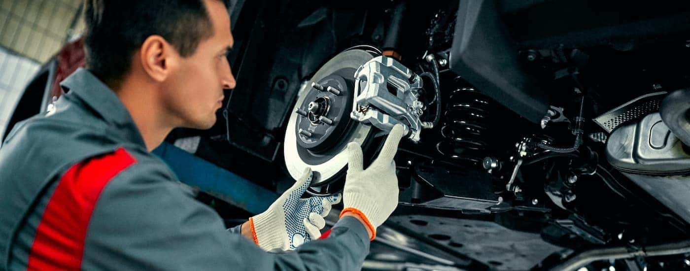 A mechanic is shown inspecting a brake caliper and rotor during a Dodge service.