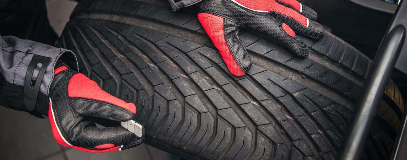 A close up shows gloved hands holding a wheel weight over a tire.